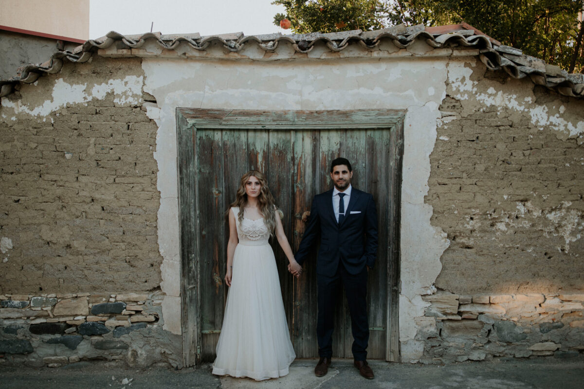 Eleni & Marinos wedding shot against a deserted village house from their wedding in Lythrodontas village