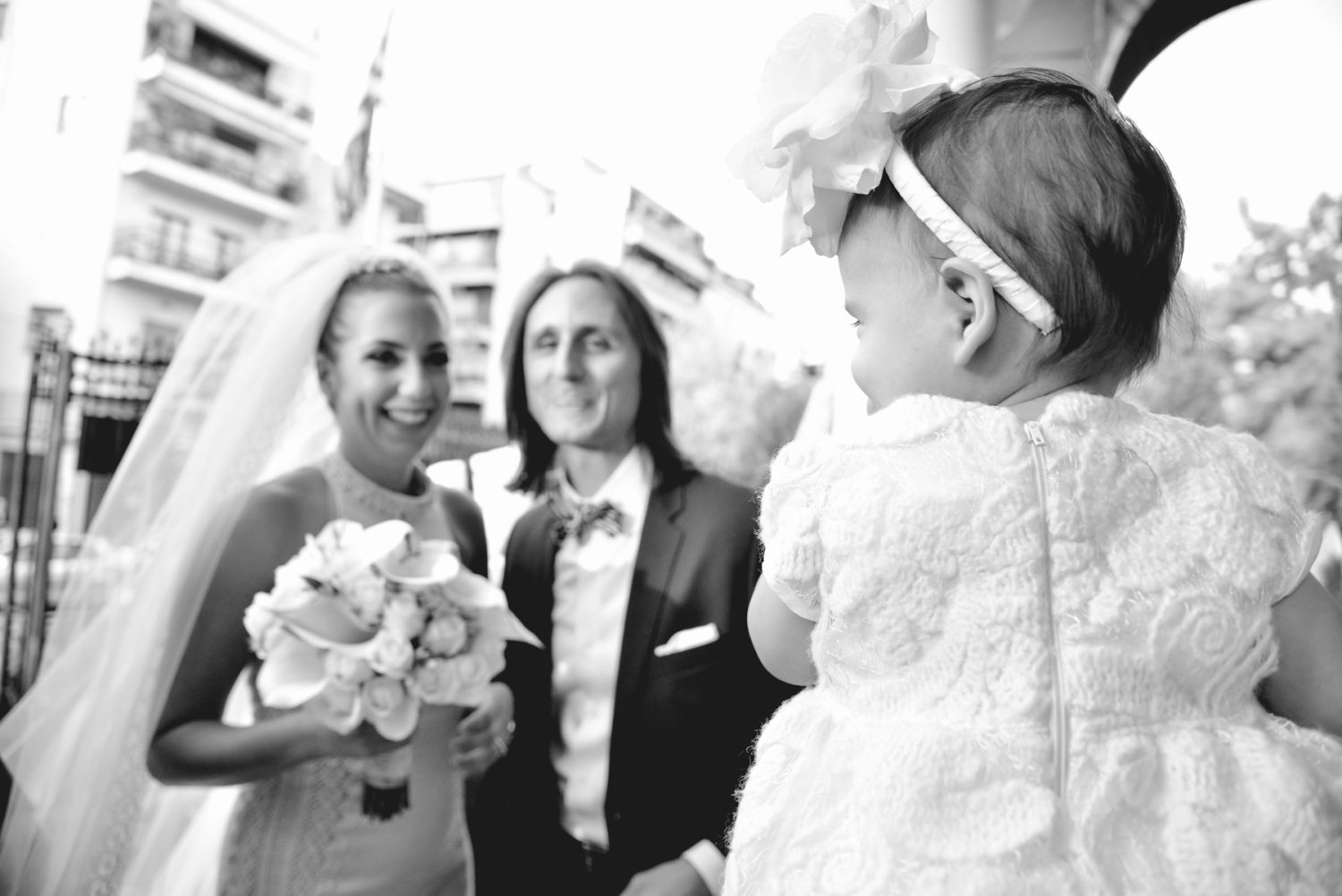 Groom and bride shot looking at their adorable baby daughter during their wedding in Agia Triada, Kerameikos