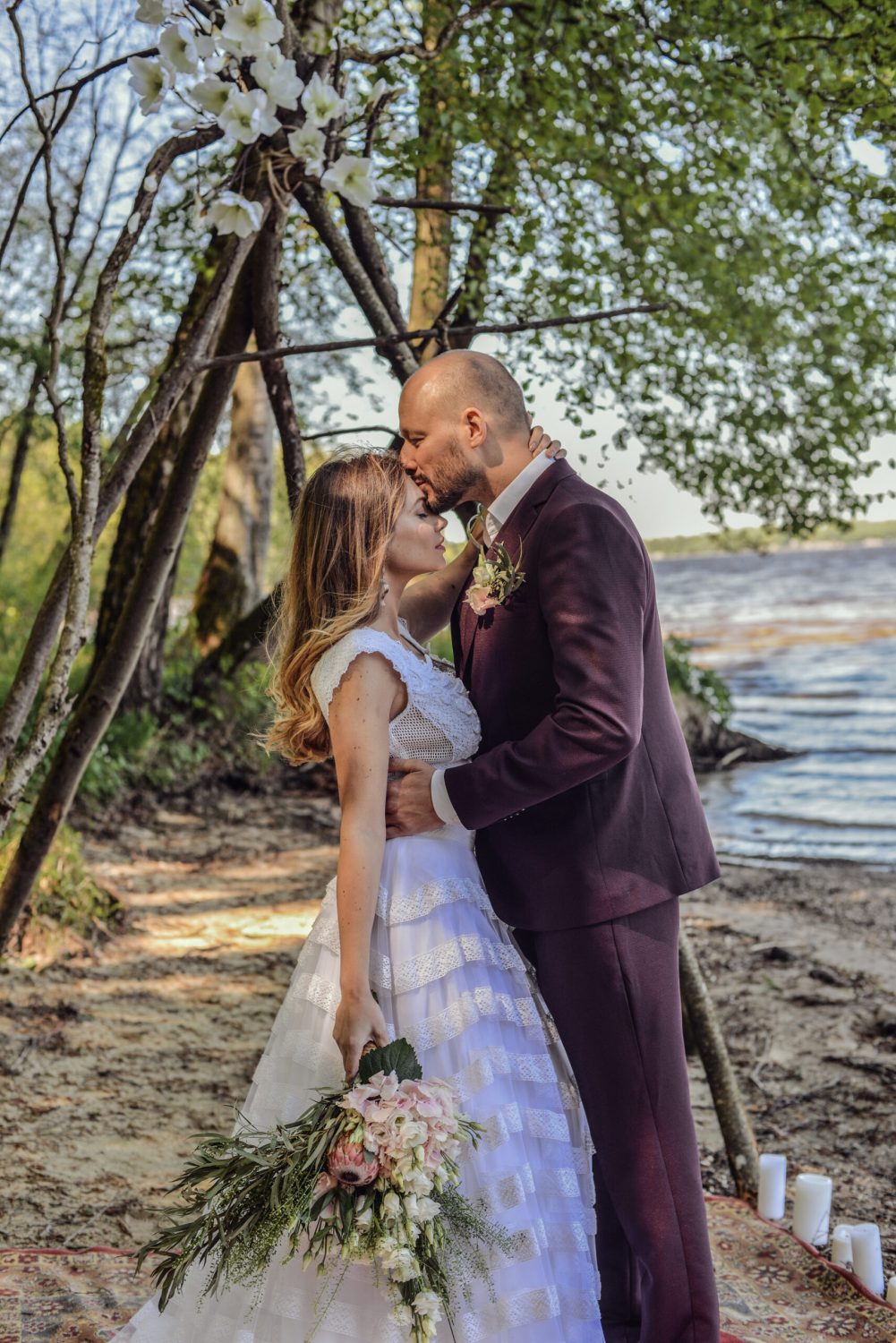 Groom kissing the forehead of the bride, who is in the handmade crop top bohemian wedding dress 'Theoni' by Atelier Zolotas