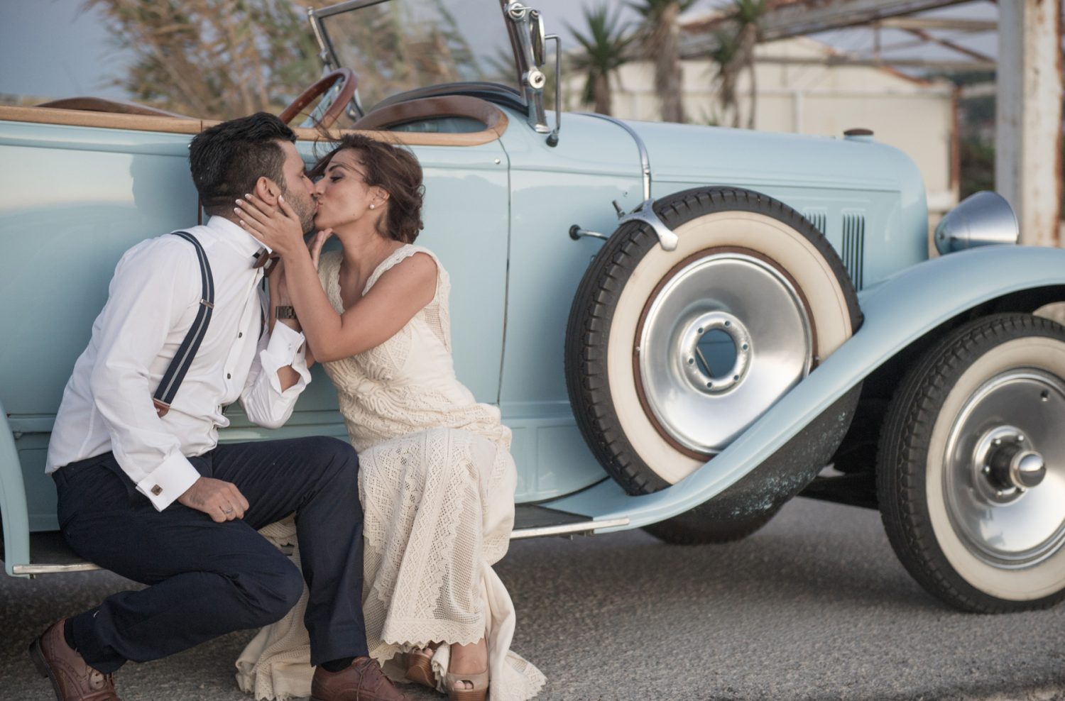 Couple kissing in front of a vintage car at their island wedding in Lefkada
