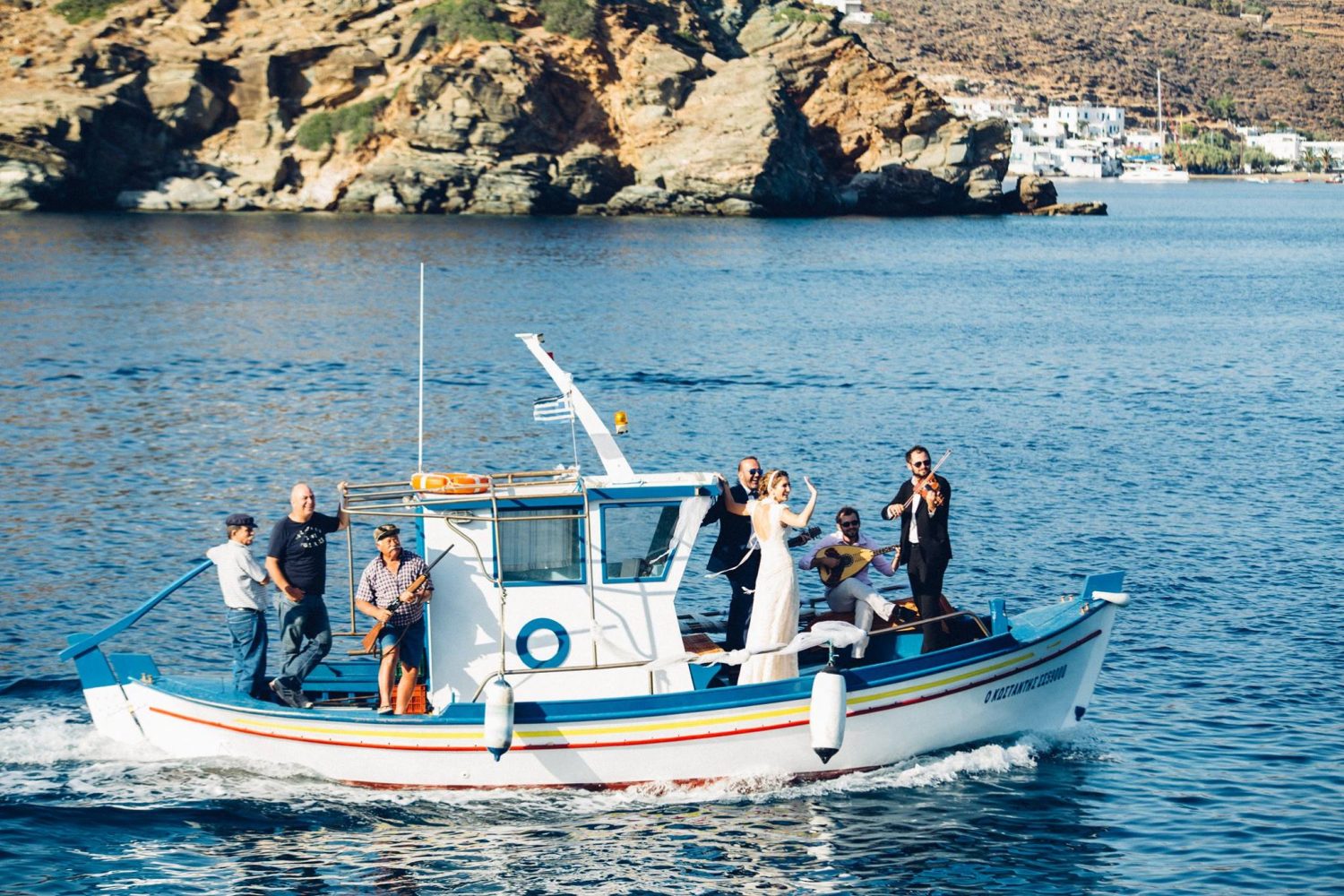 Wedding in Sifnos: Bride on a boat, on her way to the chapel of the Greek island, accompanied by an orchestra and father