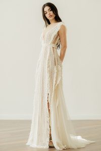 Bride wearing the Karly V-neck wedding dress by Atelier Zolotas with vintage lace, geometric trims, and removable semi-sheer sleeves in an open-back design